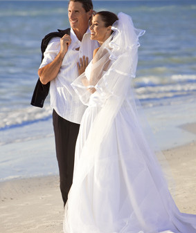 A married couple, bride and groom, together in sunshine on a beautiful tropical beach